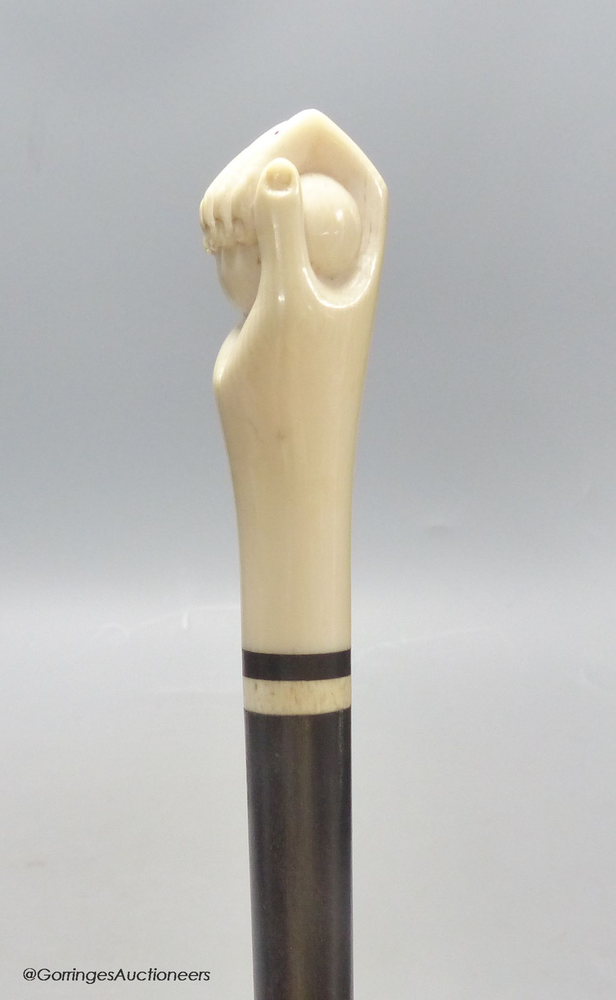 A rosewood and ivory handled walking stick in the form of a hand holding a ball